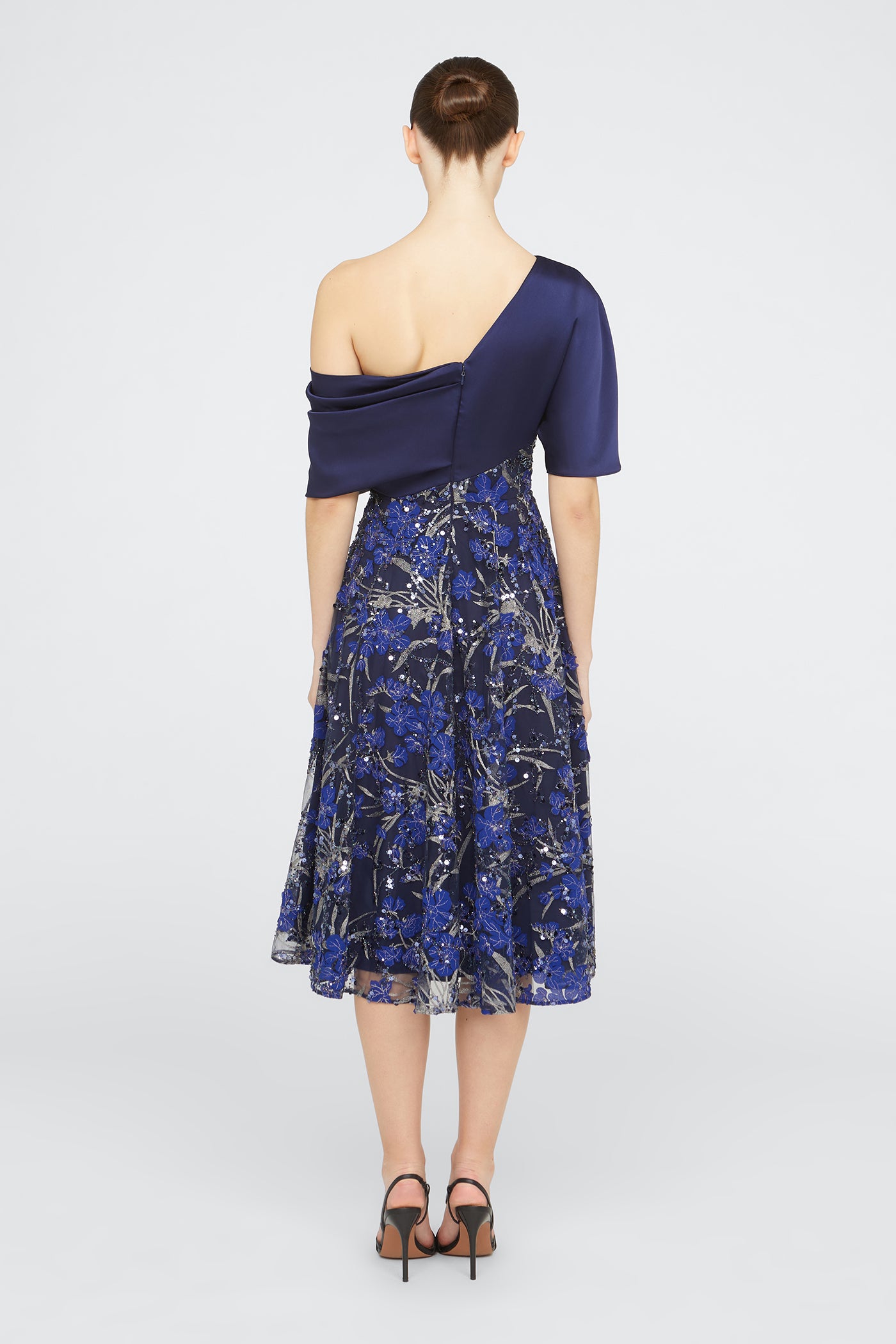 Woman wearing a blue one-shoulder dress with a floral pattern on a white background