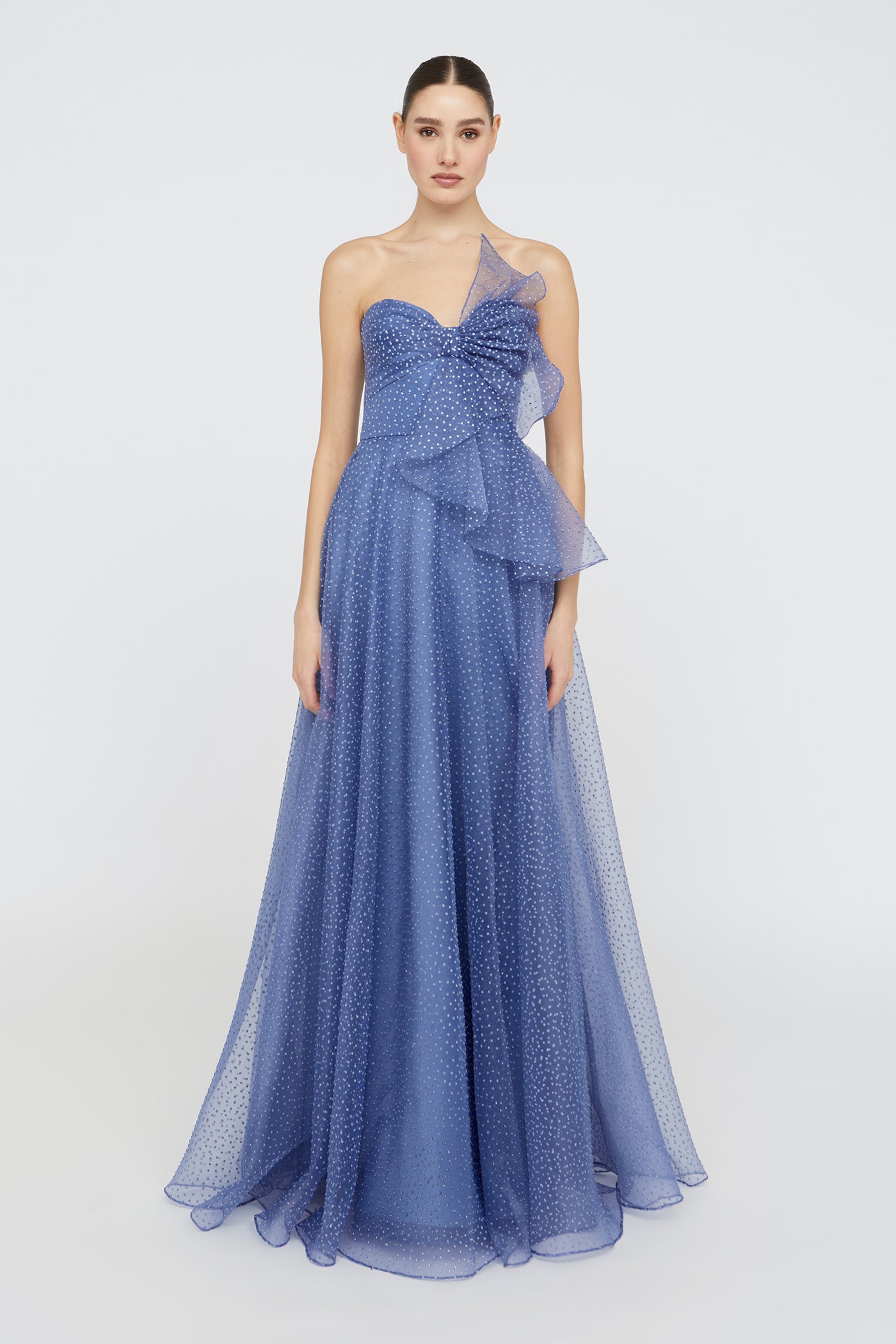 Woman wearing a blue evening gown with a ruffled design on a white background